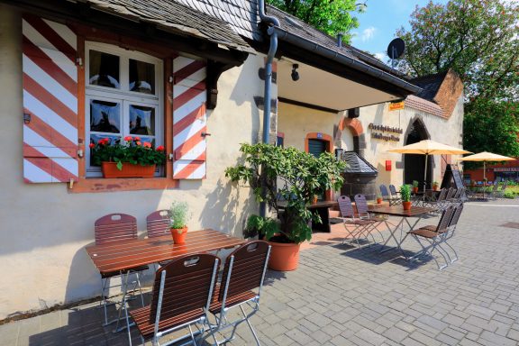 Blick auf ein gemütliches Restaurant mit Terrasse und blühenden Pflanzen.