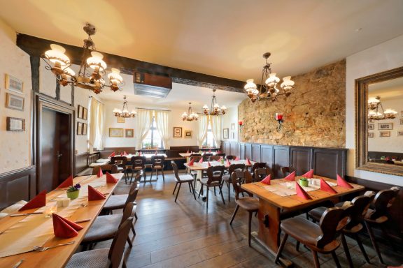 Gemütliches Restaurant mit Holztischen, Stühlen und eleganter Beleuchtung.